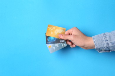 Man holding credit cards on light blue background, closeup