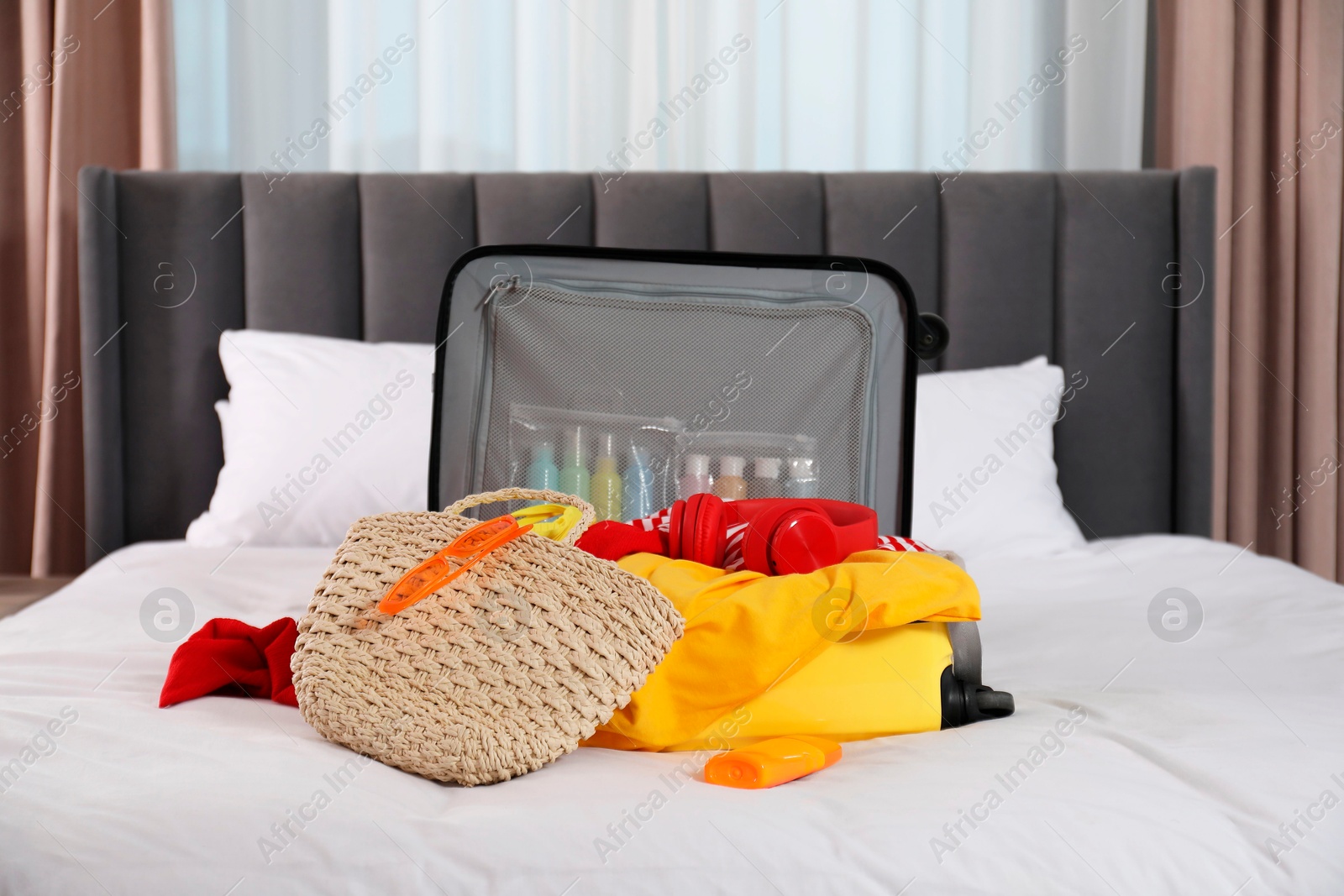 Photo of Open suitcase with traveler's belongings on bed