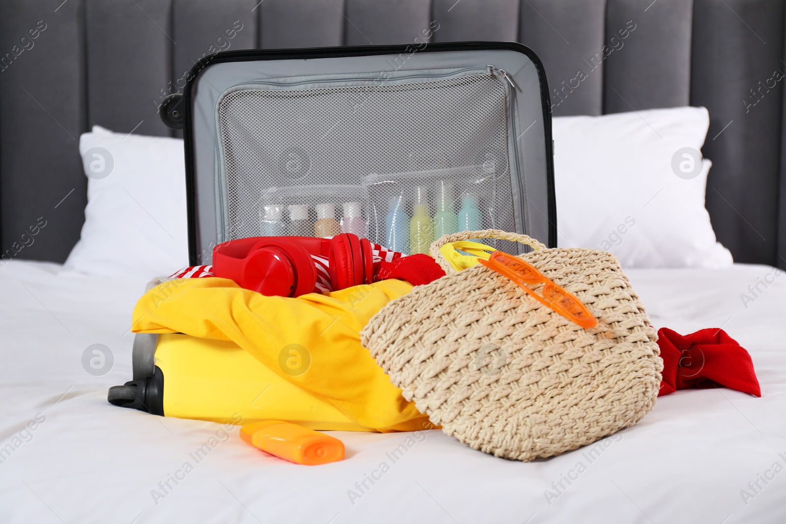 Photo of Open suitcase with traveler's belongings on bed