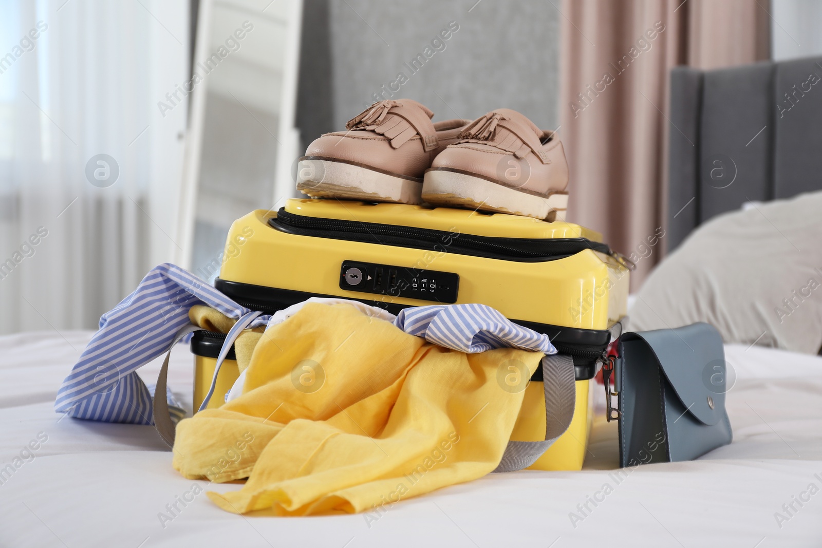 Photo of Open suitcase with traveler's belongings on bed