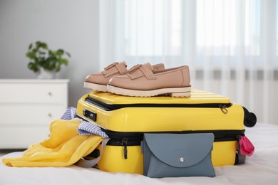 Photo of Open suitcase with traveler's belongings on bed