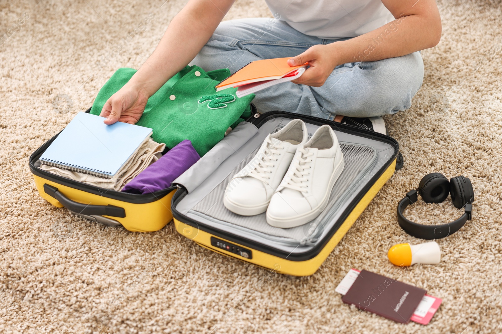 Photo of Man packing suitcase on floor at home, closeup