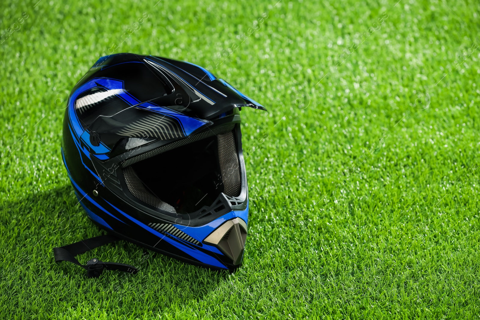 Photo of Modern motorcycle helmet with visor on green grass, space for text