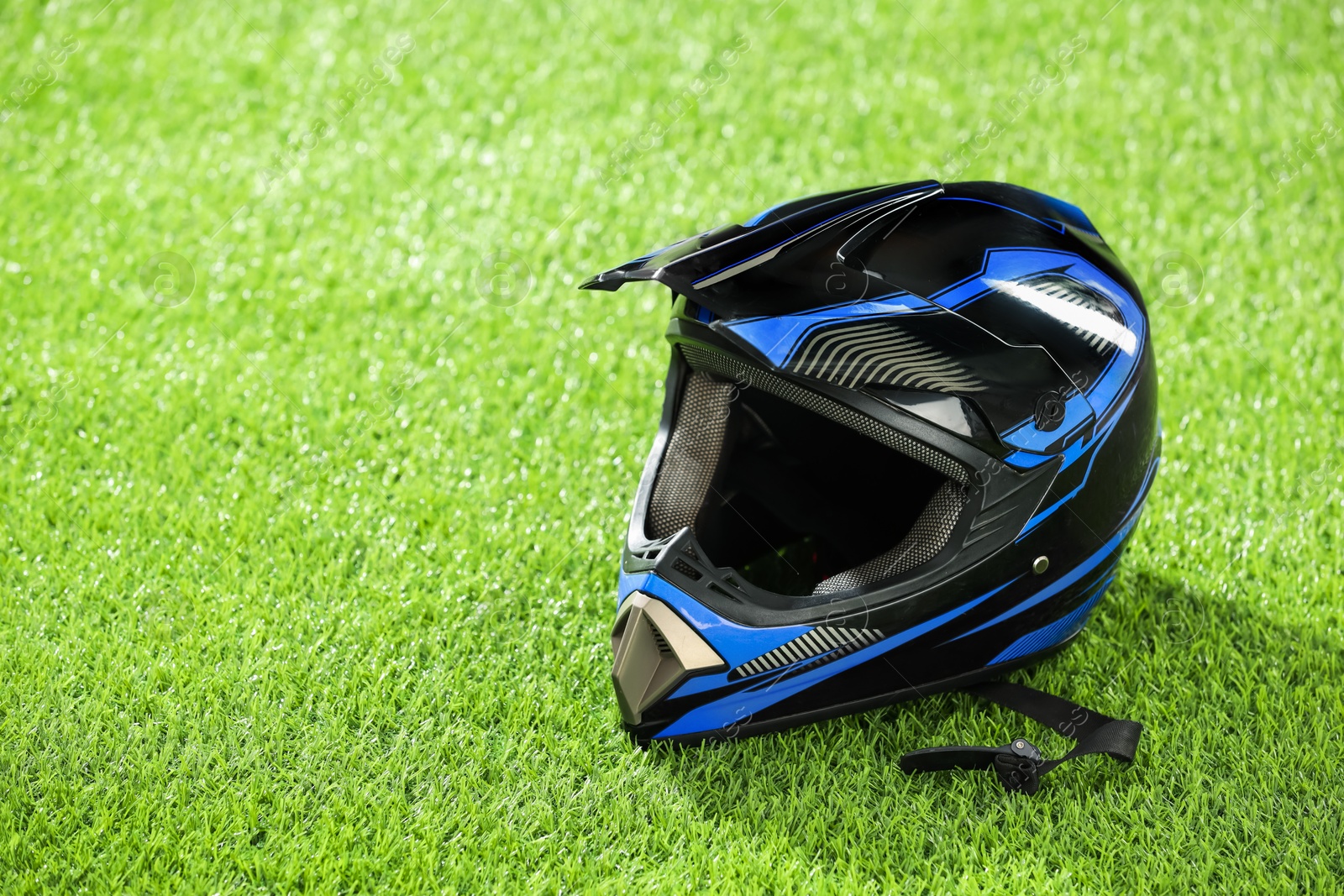 Photo of Modern motorcycle helmet with visor on green grass, space for text