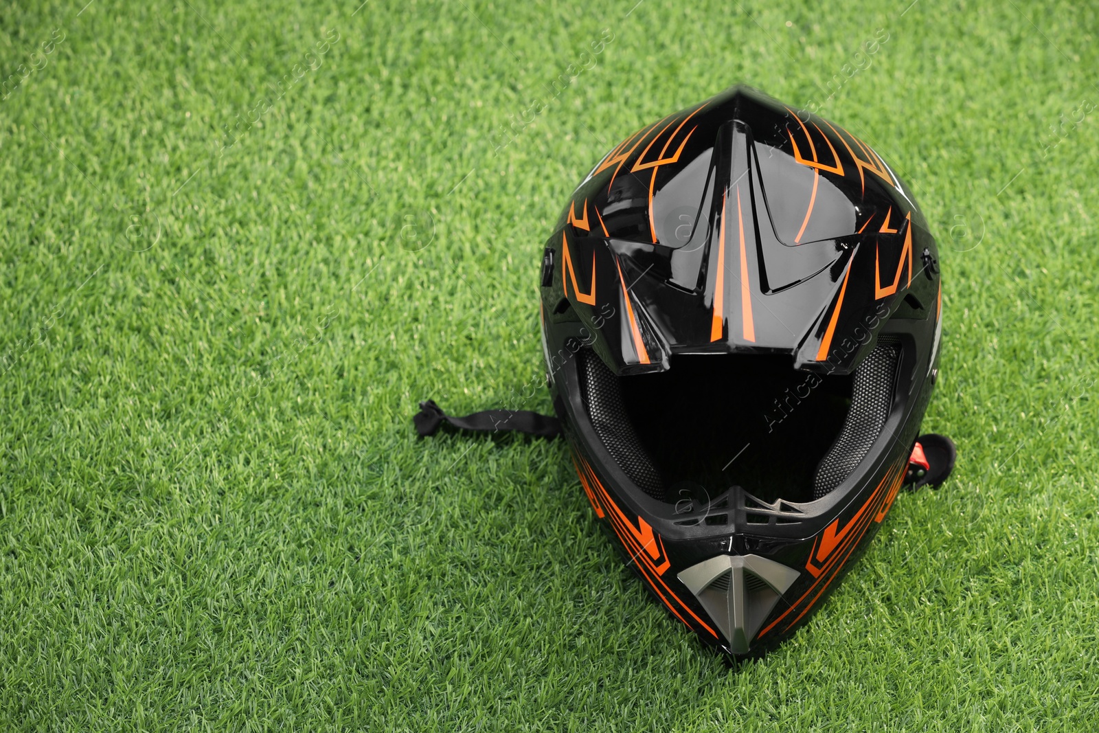 Photo of Modern motorcycle helmet with visor on green grass, space for text