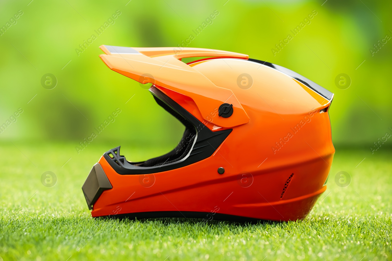 Photo of Orange motorcycle helmet with visor on green grass