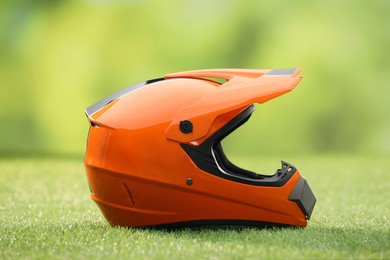 Photo of Orange motorcycle helmet with visor on green grass