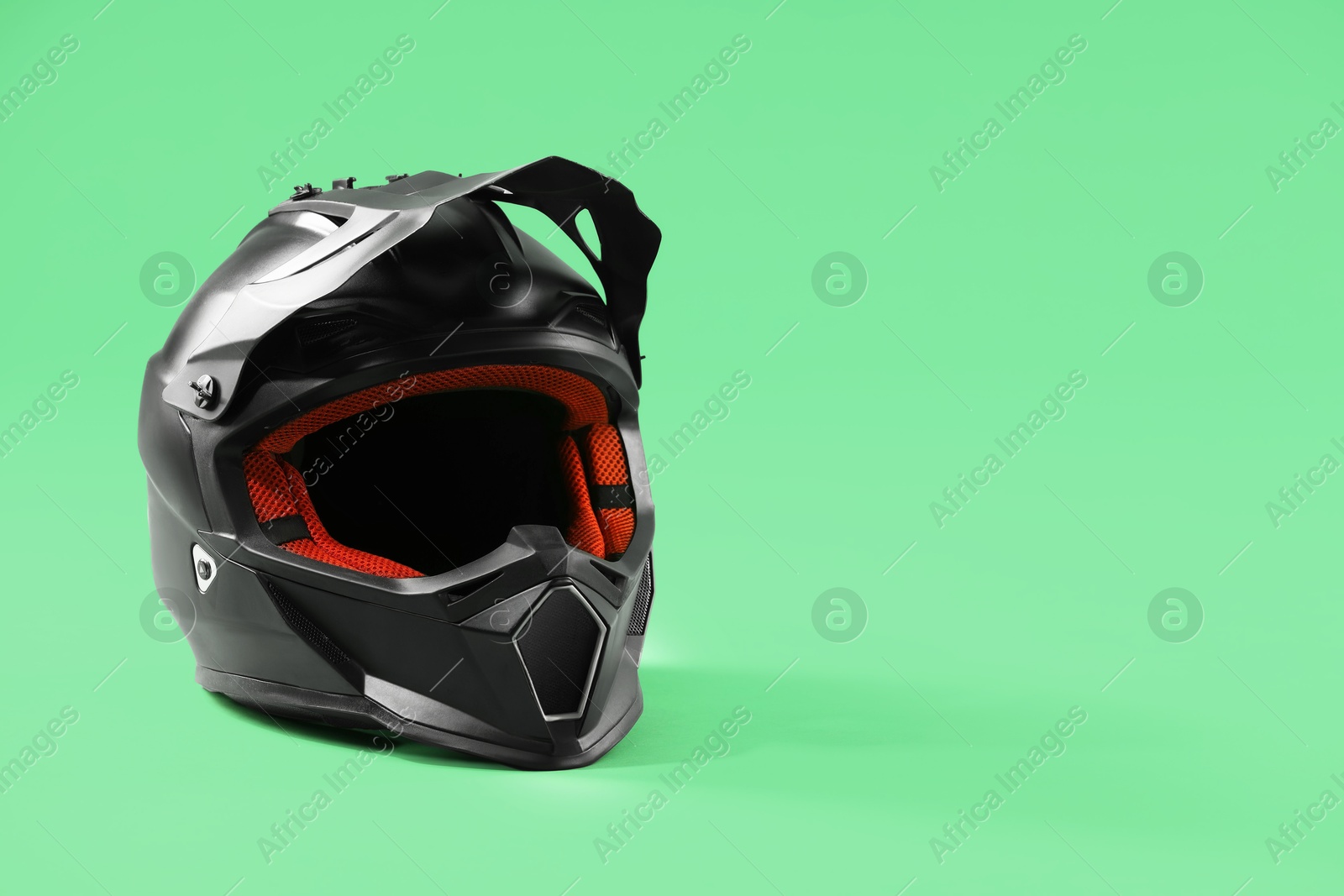 Photo of Modern motorcycle helmet with visor on light green background. Space for text