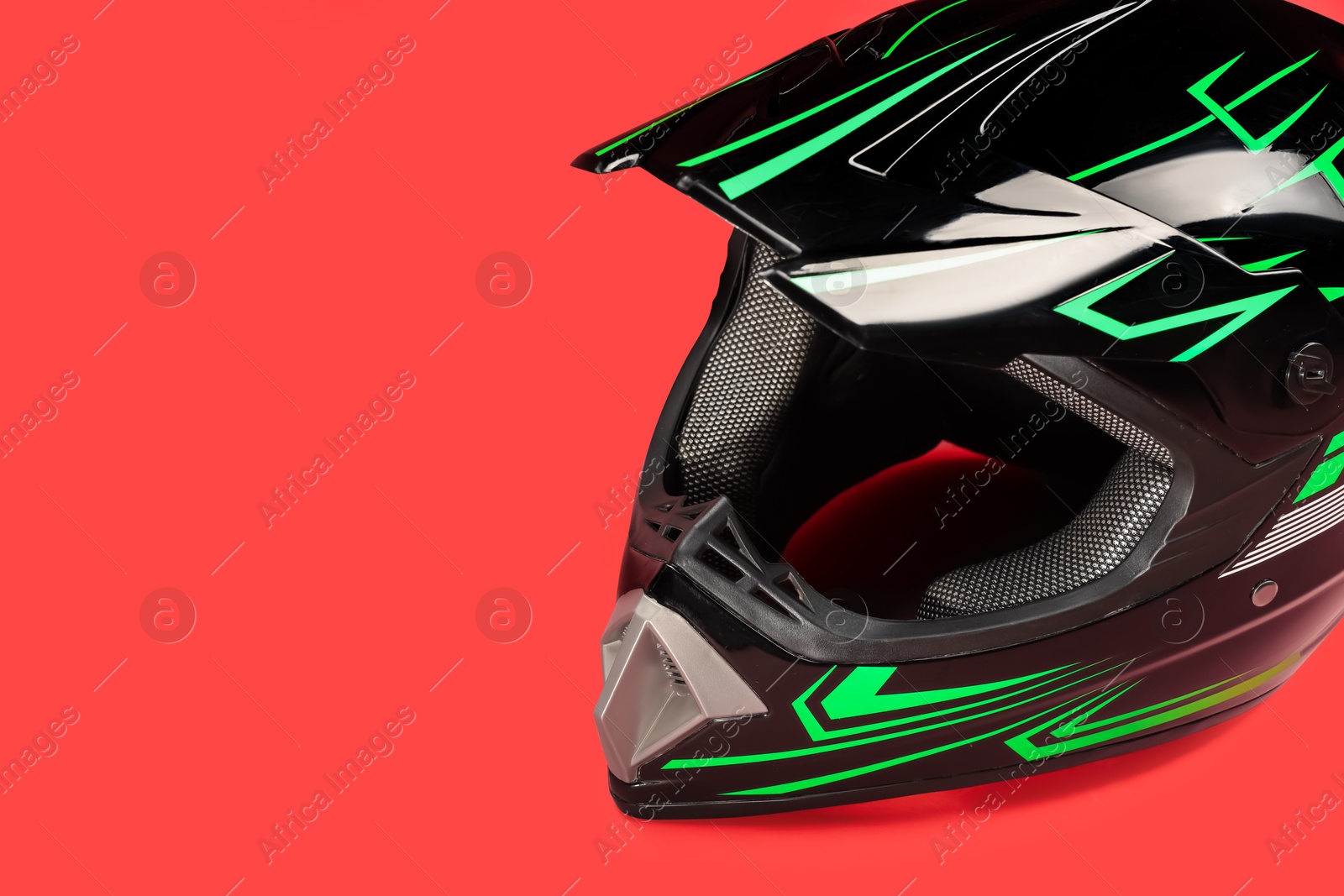 Photo of Modern motorcycle helmet with visor on red background. Space for text