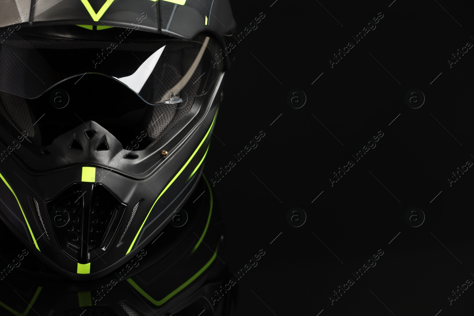Photo of Modern motorcycle helmet with visor on black background, closeup. Space for text