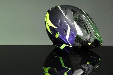 Photo of Modern motorcycle helmet with visor on mirror surface against grey background. Space for text