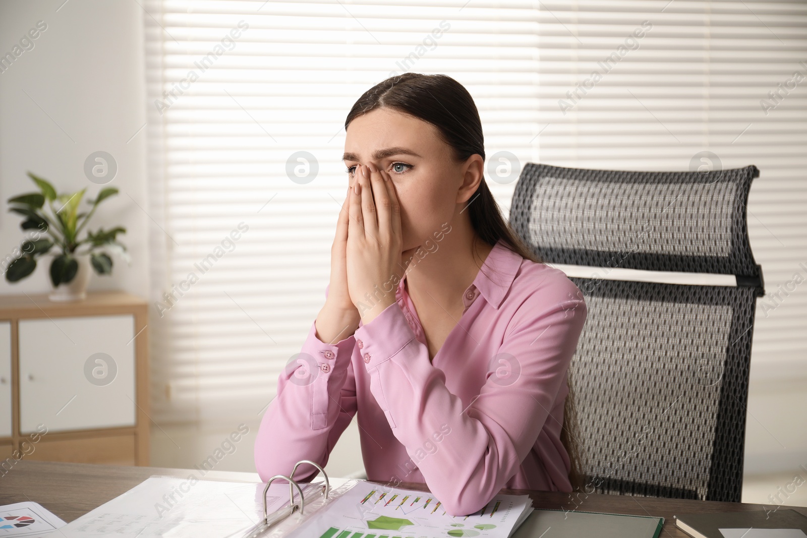 Photo of Embarrassed woman at table with documents in office, space for text