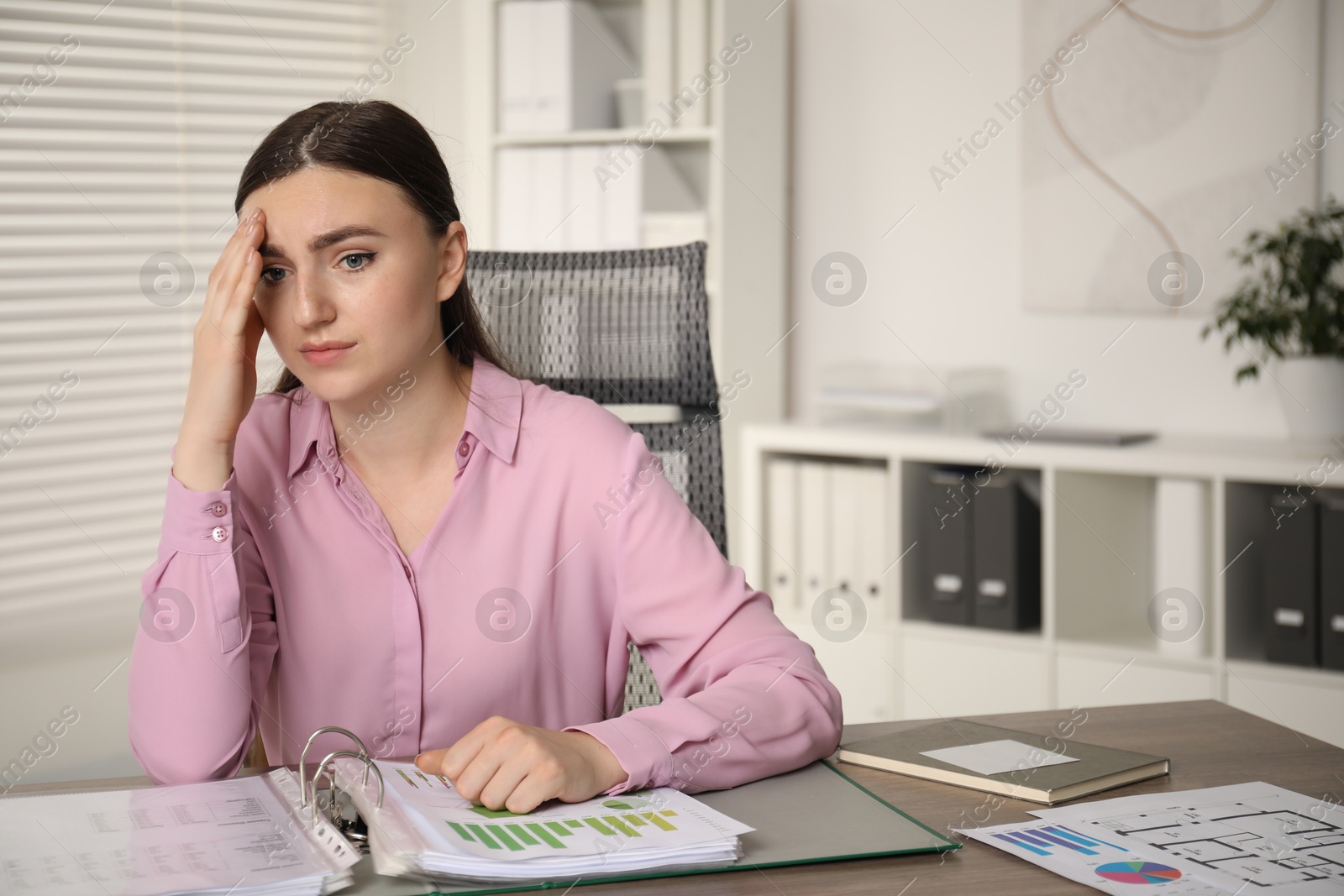 Photo of Embarrassed woman at wooden table with documents in office, space for text