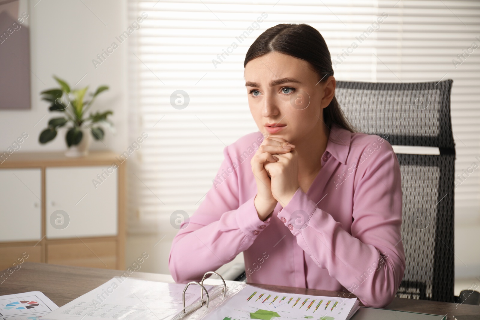 Photo of Embarrassed woman at table with documents in office, space for text