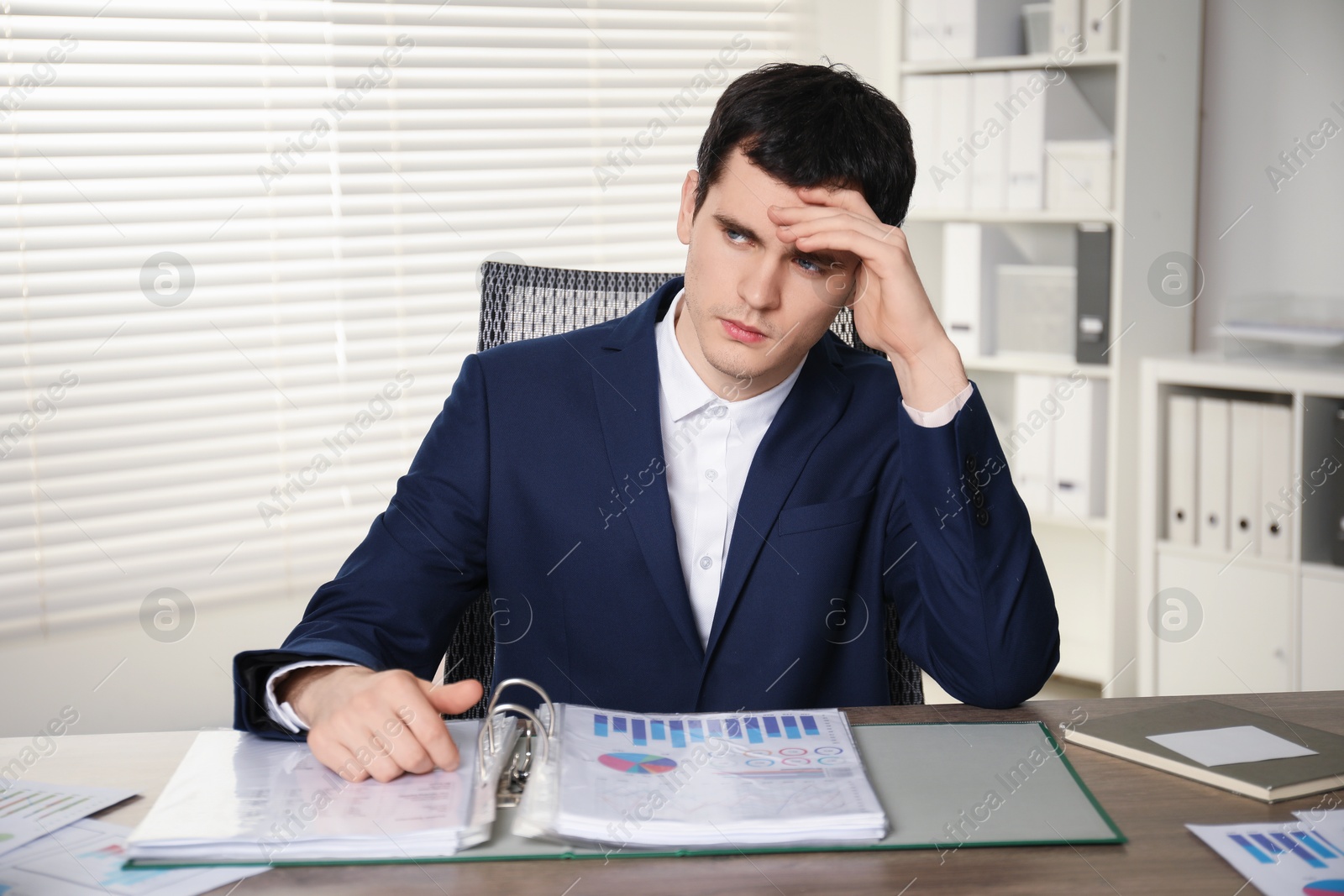 Photo of Embarrassed man at wooden table with documents in office