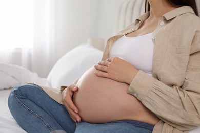 Pregnant woman on bed at home, closeup