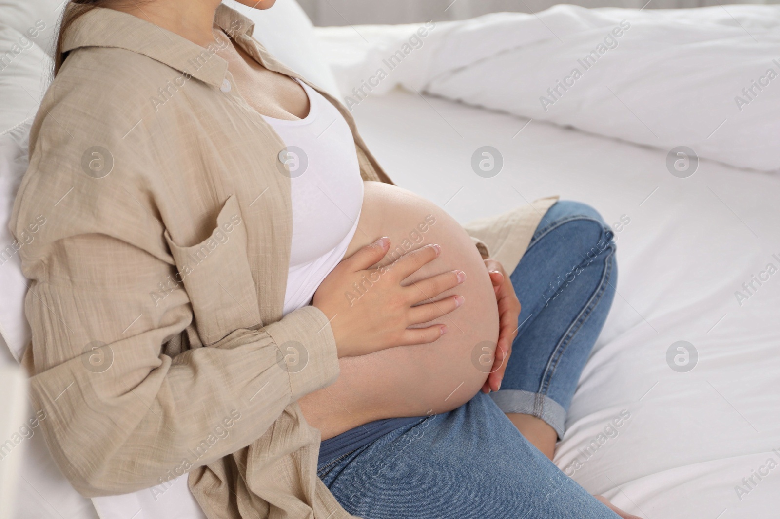 Photo of Beautiful pregnant woman on bed at home, closeup