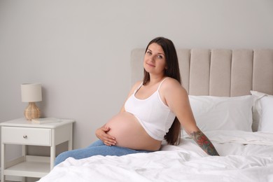 Photo of Beautiful pregnant woman on bed at home