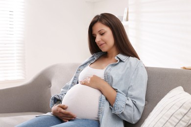 Photo of Beautiful pregnant woman sitting on sofa at home