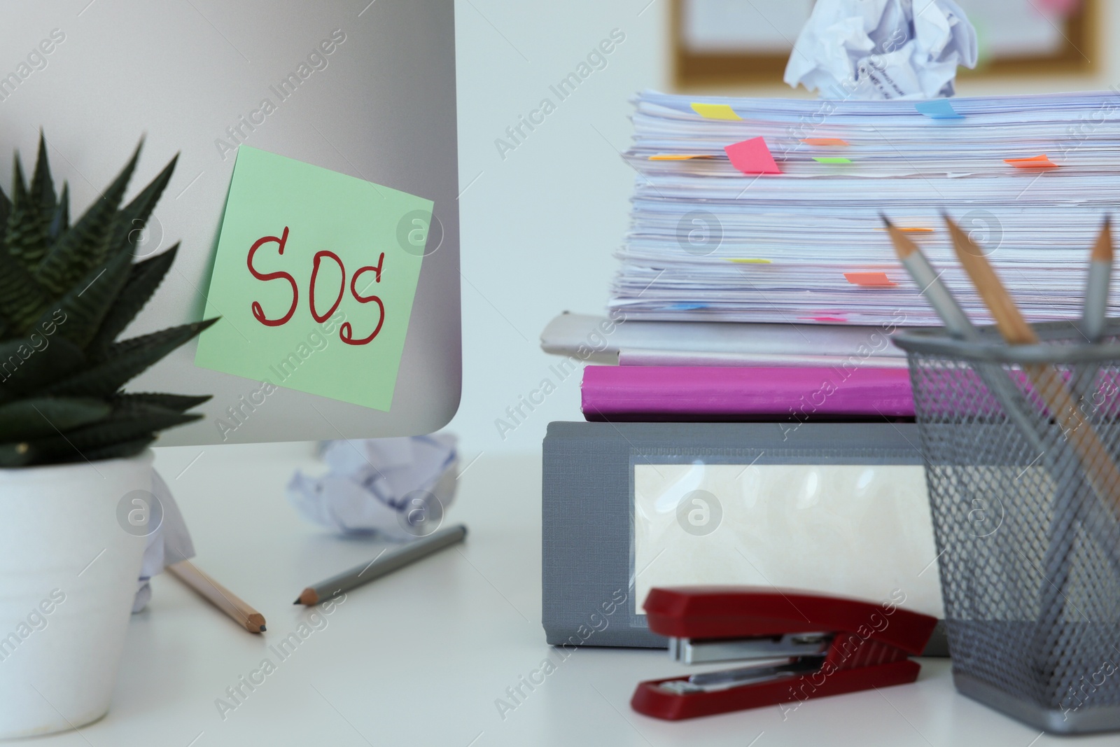 Photo of Note with word SOS and stationery on white table at workplace