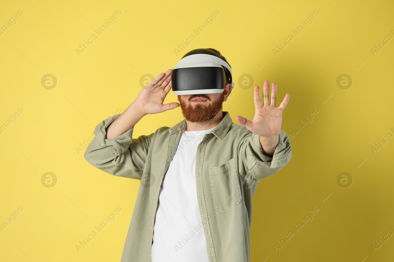 Photo of Man using virtual reality headset on pale yellow background