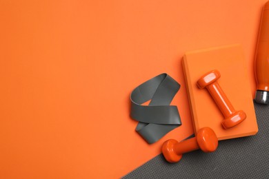 Photo of Dumbbells, yoga block, mat, thermo bottle and fitness elastic band on orange background, flat lay. Space for text