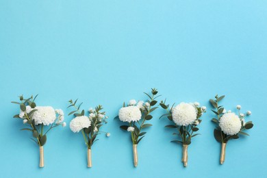 Photo of Many stylish boutonnieres on light blue background, flat lay. Space for text