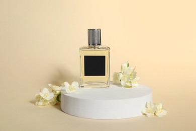 Photo of Presentation of aromatic perfume in bottle and beautiful jasmine flowers against beige background