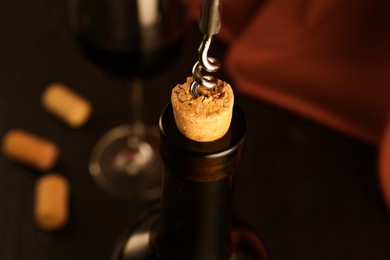 Photo of Wine bottle with corkscrew on blurred background, closeup