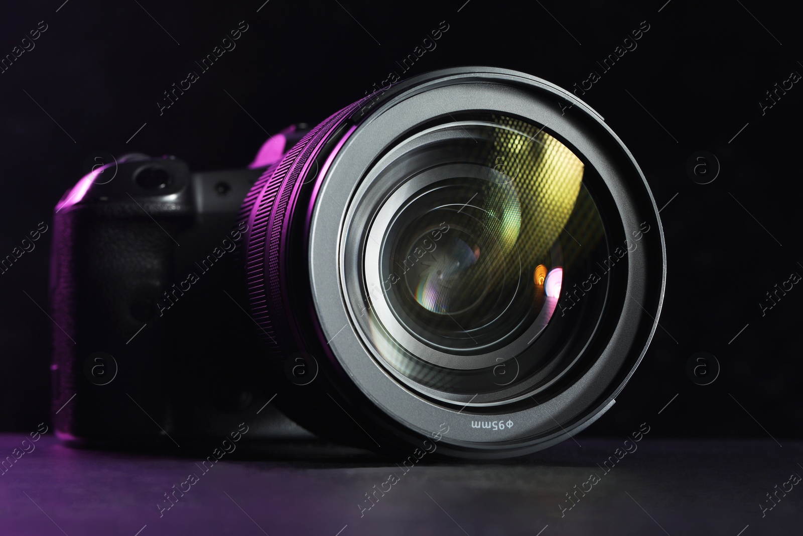 Photo of Modern photo camera on black table, closeup. Photographer's equipment