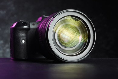 Modern photo camera on black table. Photographer's equipment