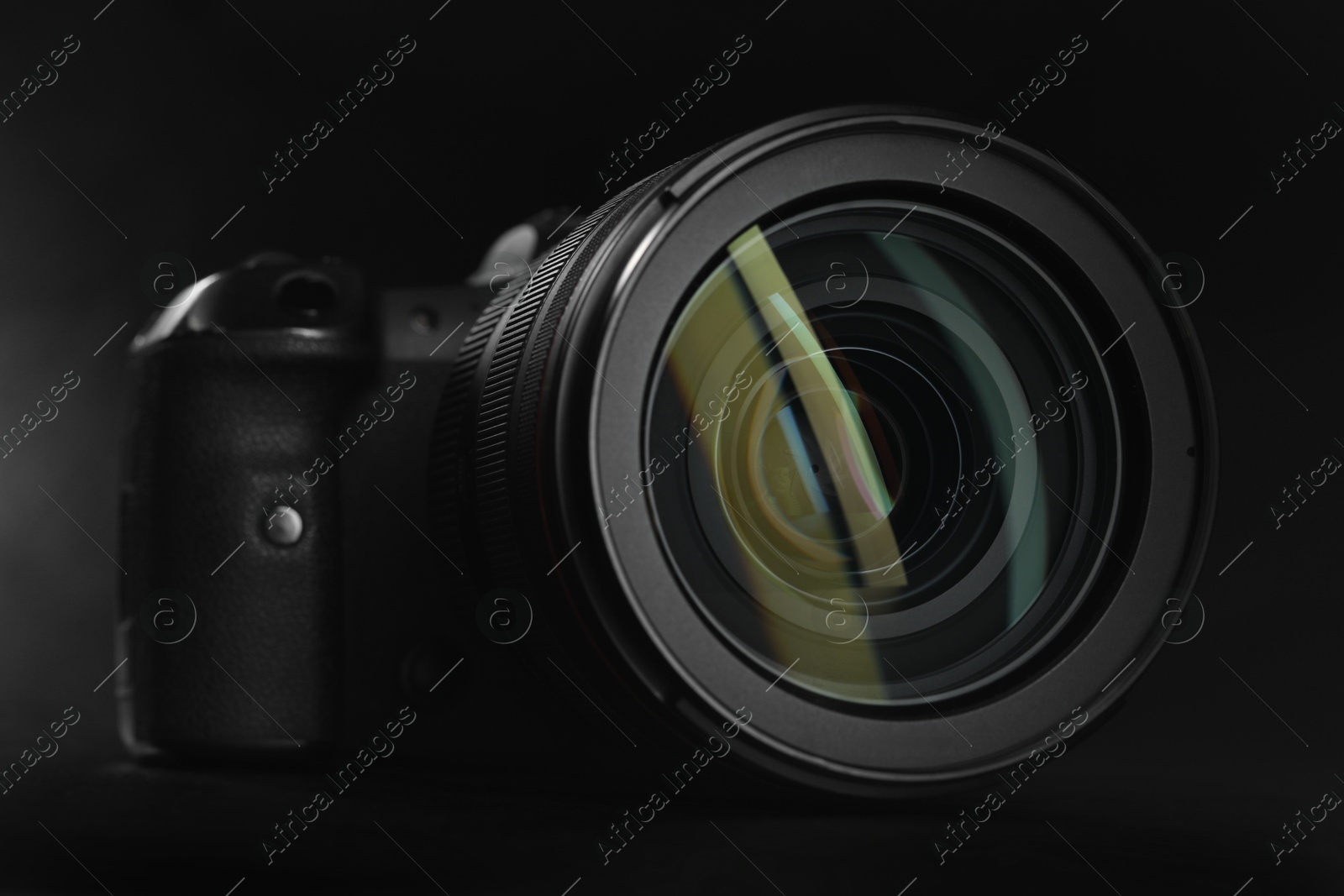 Photo of Modern photo camera on black table, closeup. Photographer's equipment