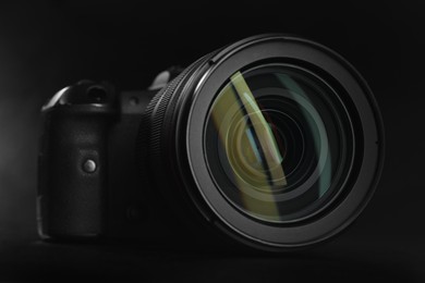 Photo of Modern photo camera on black table, closeup. Photographer's equipment