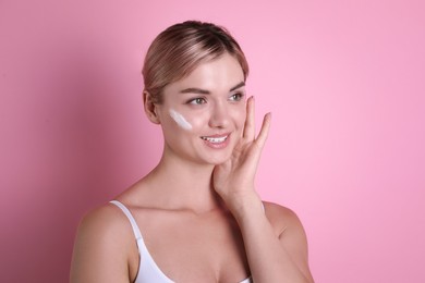 Photo of Beautiful woman with cream on her face against pink background