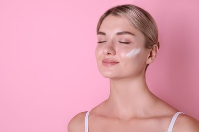 Photo of Beautiful woman with cream on her face against pink background, space for text