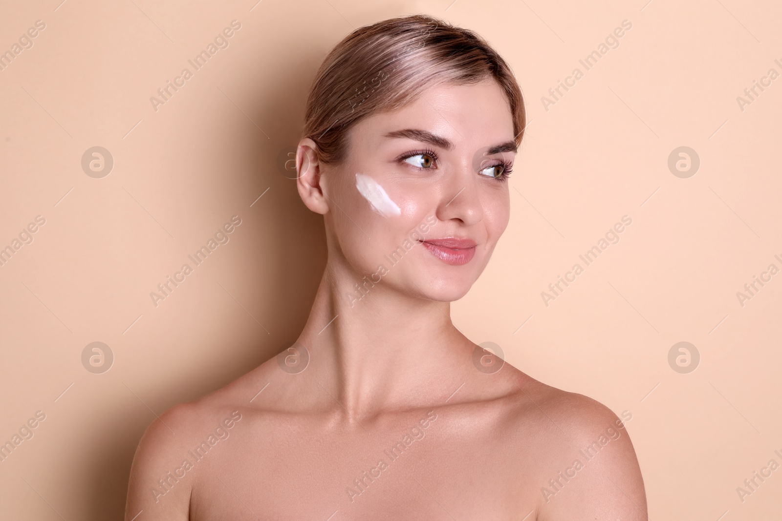 Photo of Beautiful woman with cream on her face against beige background