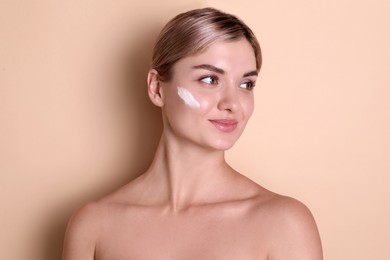 Photo of Beautiful woman with cream on her face against beige background