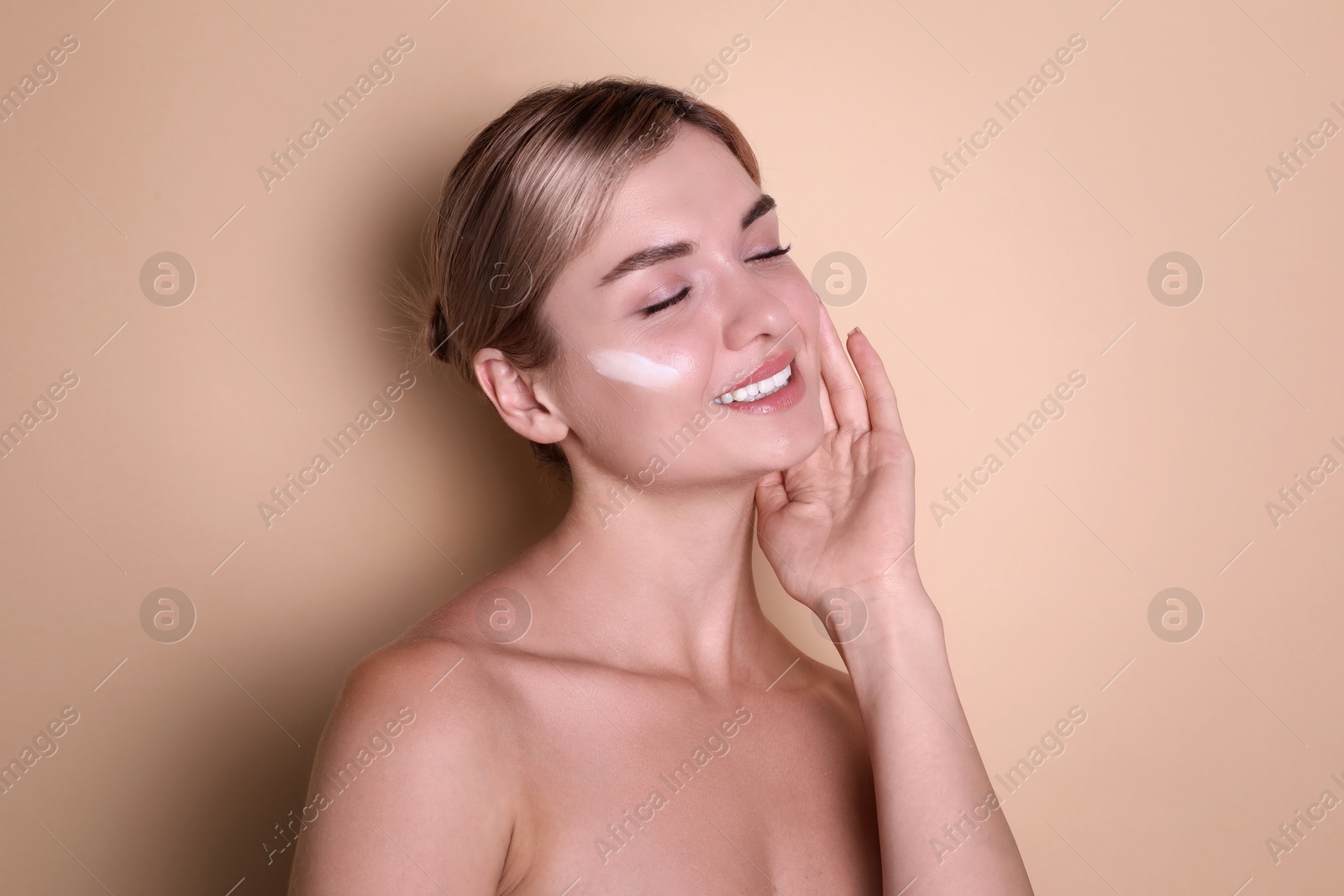 Photo of Beautiful woman with cream on her face against beige background