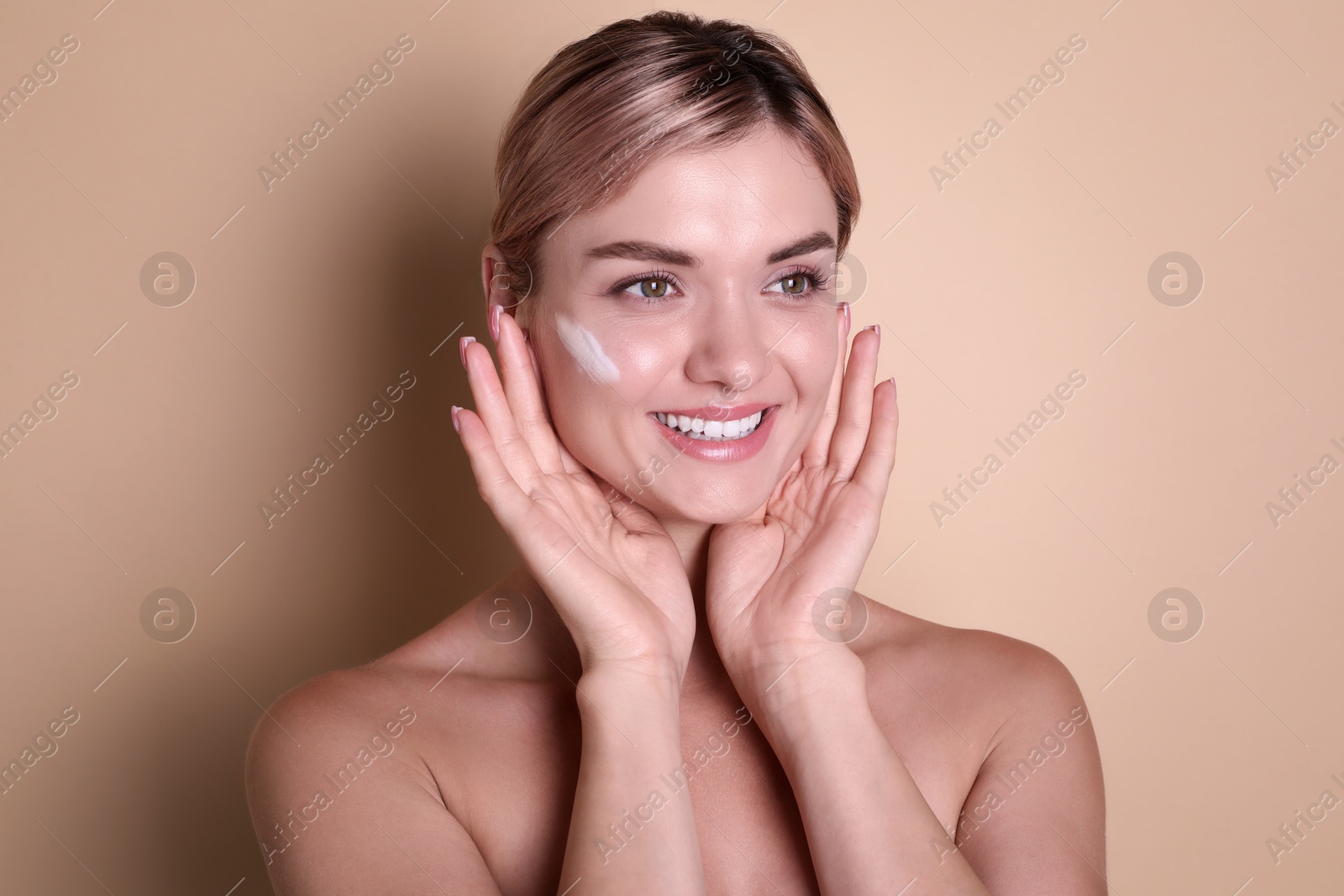 Photo of Beautiful woman with cream on her face against beige background