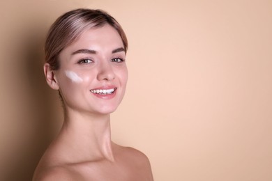 Photo of Beautiful woman with cream on her face against beige background, space for text