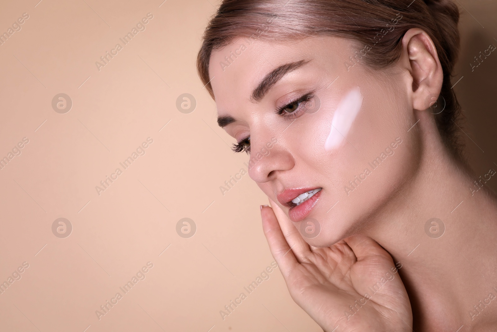 Photo of Beautiful woman with cream on her face against beige background, closeup. Space for text