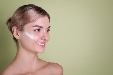 Photo of Beautiful woman with cream on her face against light green background, space for text