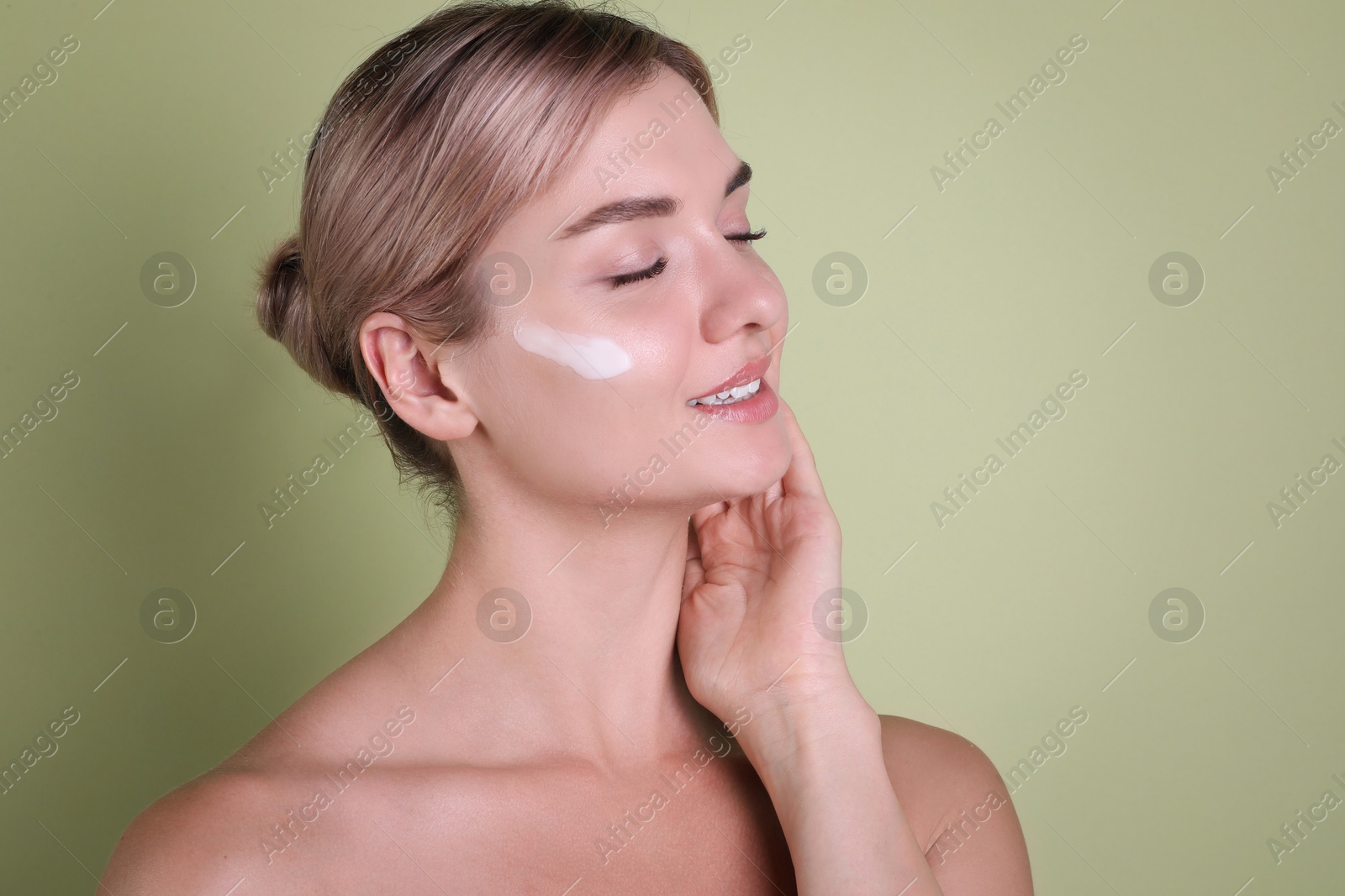 Photo of Beautiful woman with cream on her face against light green background, space for text