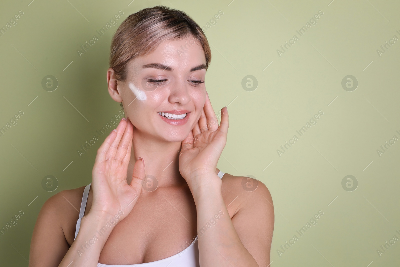 Photo of Beautiful woman with cream on her face against light green background, space for text