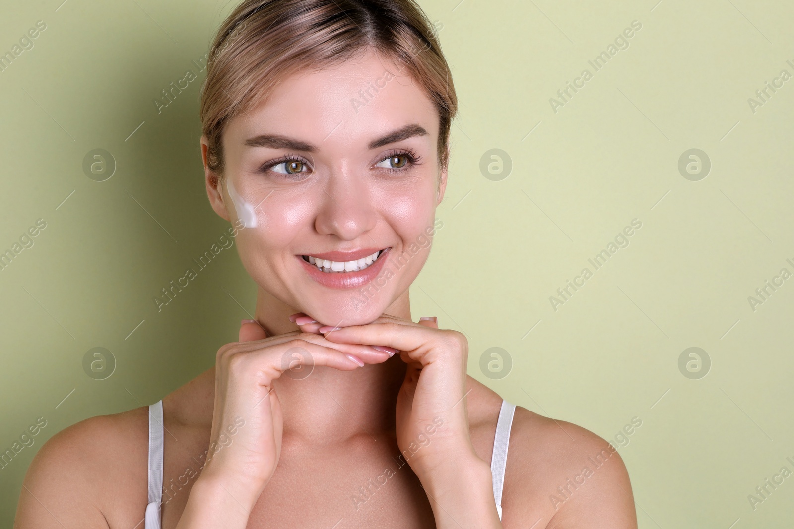 Photo of Beautiful woman with cream on her face against light green background, space for text