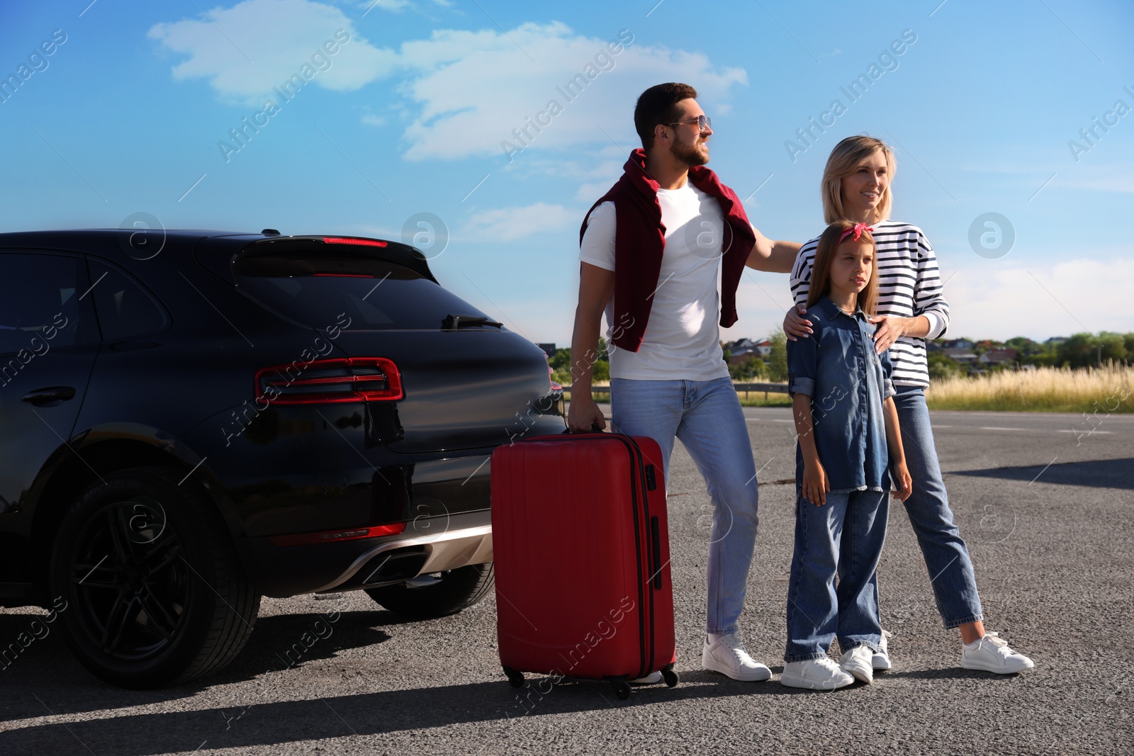 Photo of Happy family with red suitcase near car outdoors