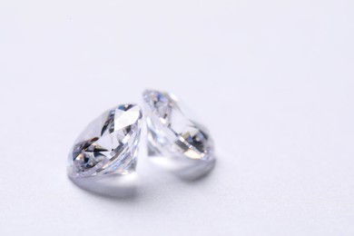 Photo of Two beautiful shiny diamonds on white background, closeup. Space for text