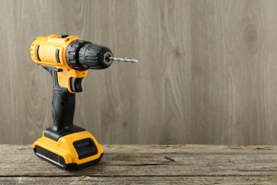 Photo of One cordless electric drill on wooden table, space for text