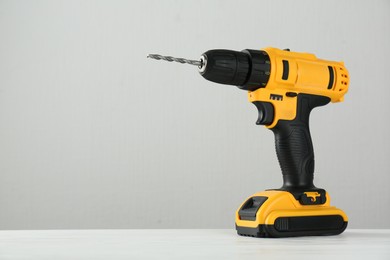 One cordless electric drill on white wooden table, space for text