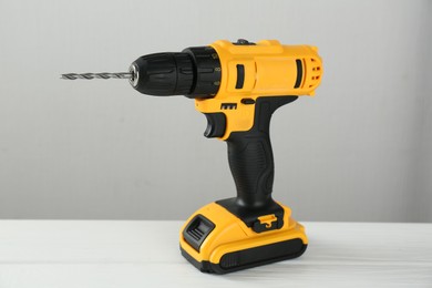 Photo of One cordless electric drill on white wooden table